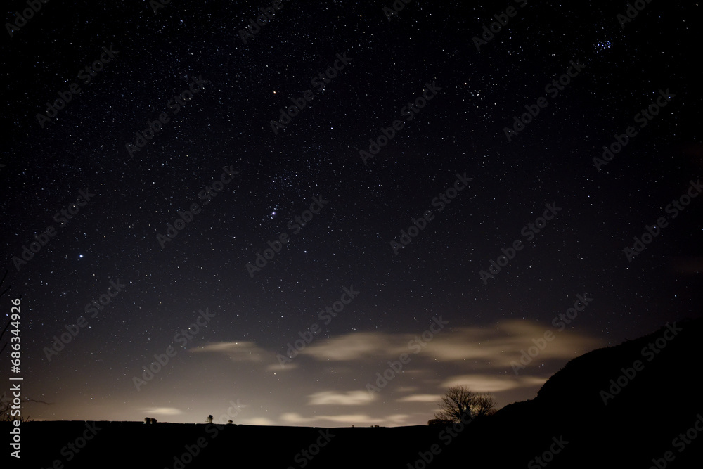 Night sky view of bright stars in space over landscape countryside scene