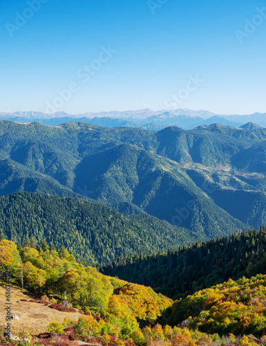 Beautiful mountain landscape with color trees, blue sky and snow peaks in sunny day. Traveling through the mountains of Georgia.
