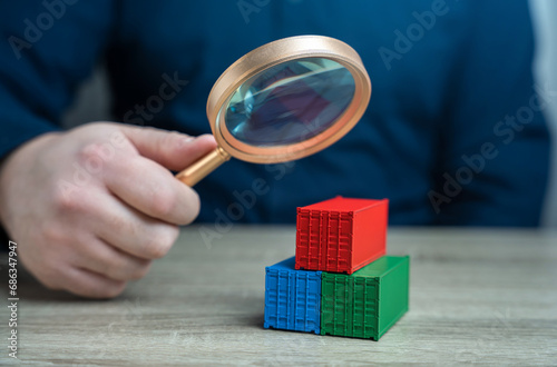 Examining cargo containers through a magnifying glass. Studying the origin of goods and delivery routes. Counteraction to circumvention of sanctions, transportation of drugs and prohibited goods. photo