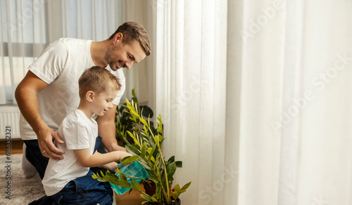 Father is teaching his son about chores and how to take care of houseplants. photo
