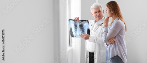 Senior doctor with x-ray image of lungs and female patient in clinic. Banner for design