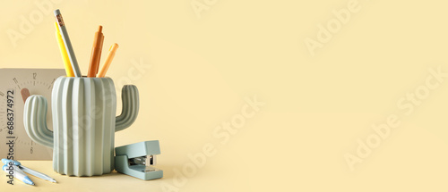 Stylish holder with stationery and clock on beige background with space for text