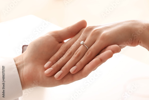 Engaged couple holding hands at table, closeup