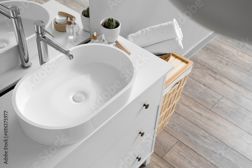 White sink with bath accessories and basket in light bathroom, closeup