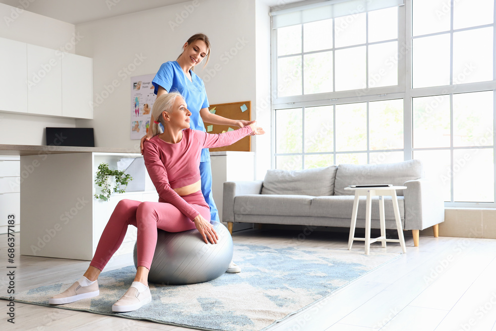 Female physiotherapist working with mature woman on fitball in rehabilitation center Female physiotherapist working with mature woman on fitball in rehabilitation center