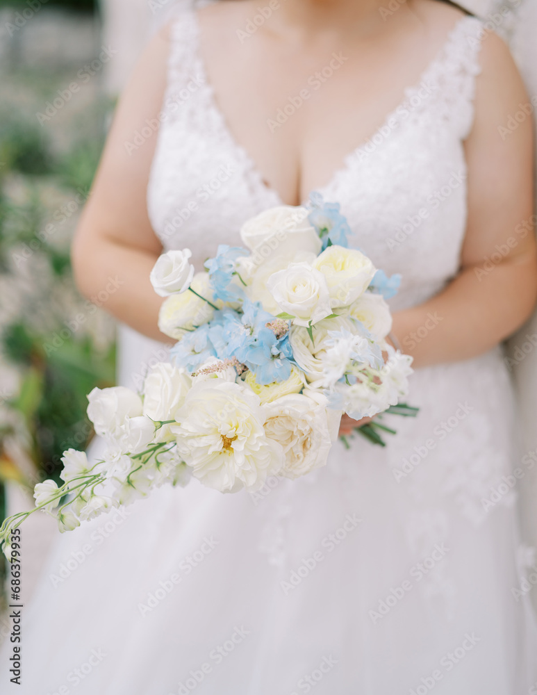 Bouquet of flowers in the hands of a bride in a lace dress. Cropped. Faceless