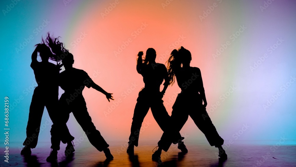 In the frame on a purple, orange background, gradient. Dancing group consisting of attractive, girls, in silhouette. They demonstrate dance moves in the direction of jazz funk.