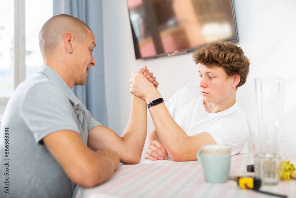 Obraz premium Father arm wrestling his son. They're happy and havung fun.