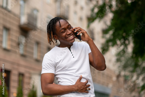 a joyful smiling young man talking on the phone in the street