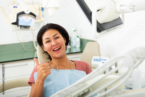 Portrait of smiling satisfied asian woman visiting dentist giving thumbs up