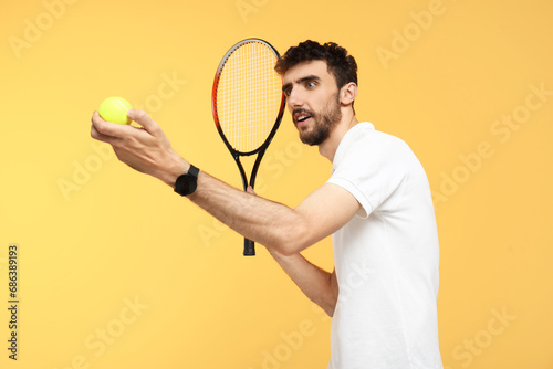 Young man with tennis racket and ball on yellow background © Pixel-Shot