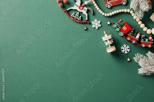 Retro style Christmas composition with wooden toys and garland on green background. Vintage greeting card design. Flat lay, top view.