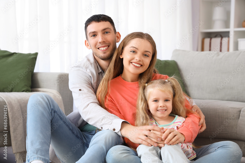 Happy parents with their little daughter hugging at home