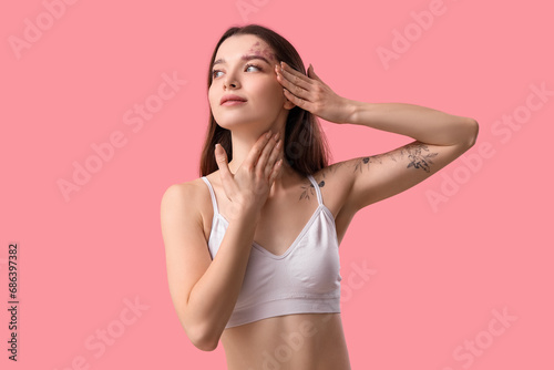 Young woman doing face building exercise on pink background