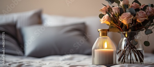 On Valentine s Day morning there s a luxurious scent emanating from a reed diffuser on the gray table in the bedroom next to a scented candle and the gray bed photo