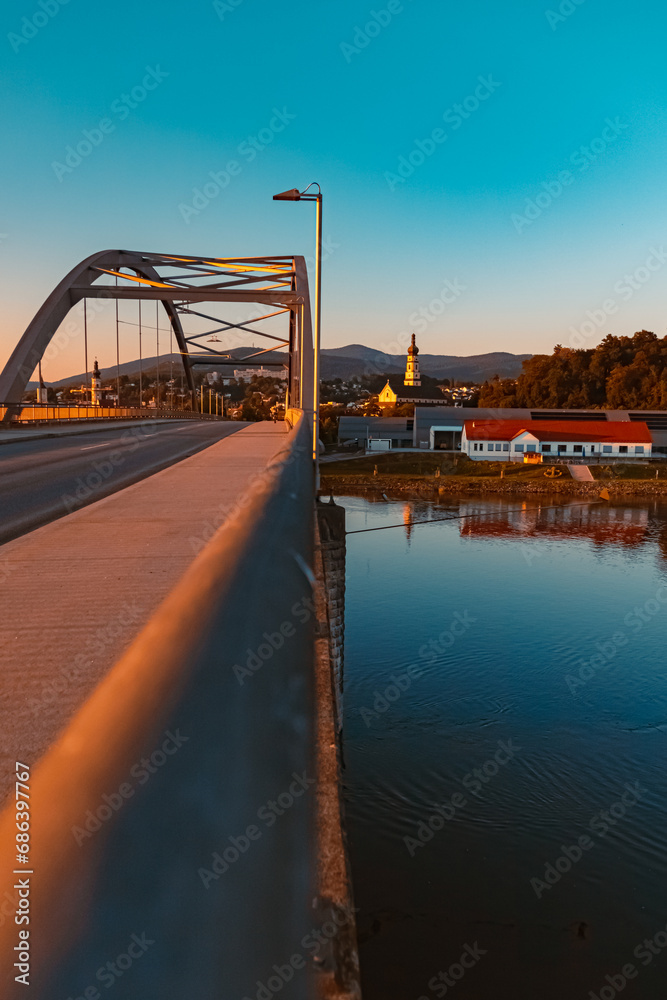 Obraz premium Sunset with a bridge, a church and reflections near Deggendorf, Danube, Bavaria, Germany