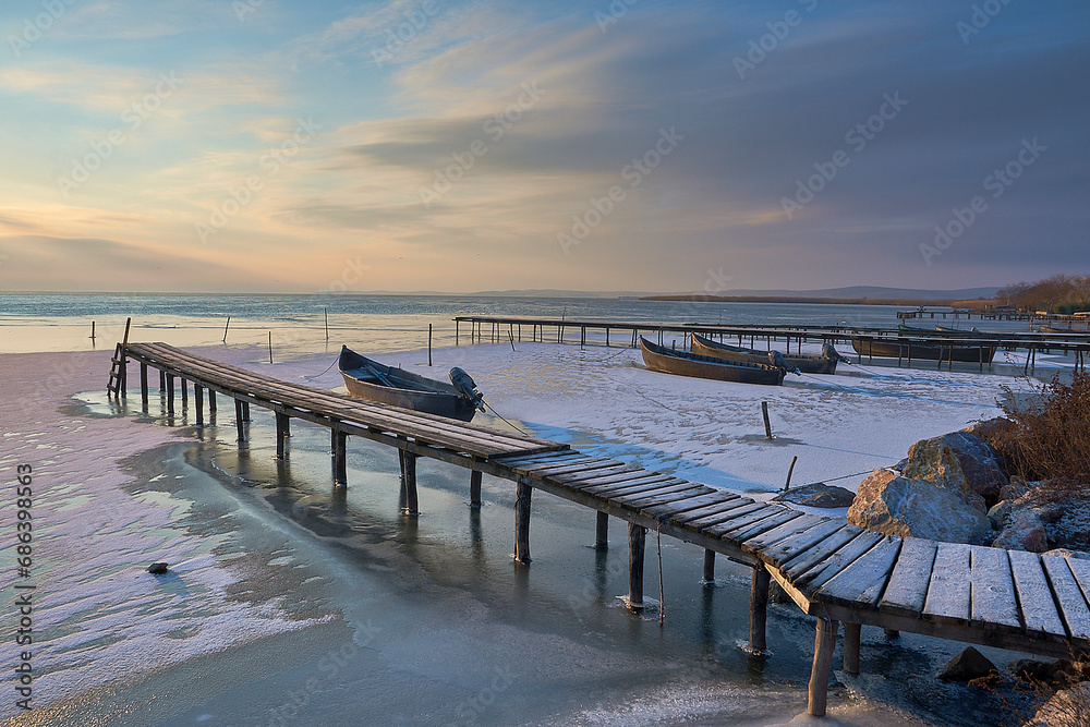frozen boat in winter on the lake at sunrise
