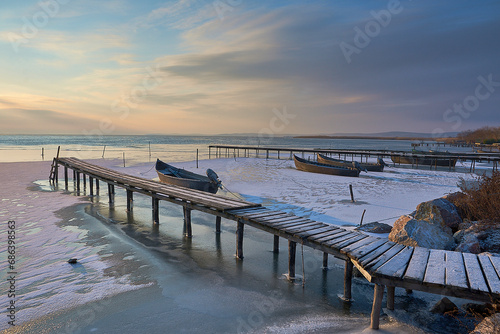 Obraz na płótnie frozen boat in winter on the lake at sunrise w salonie