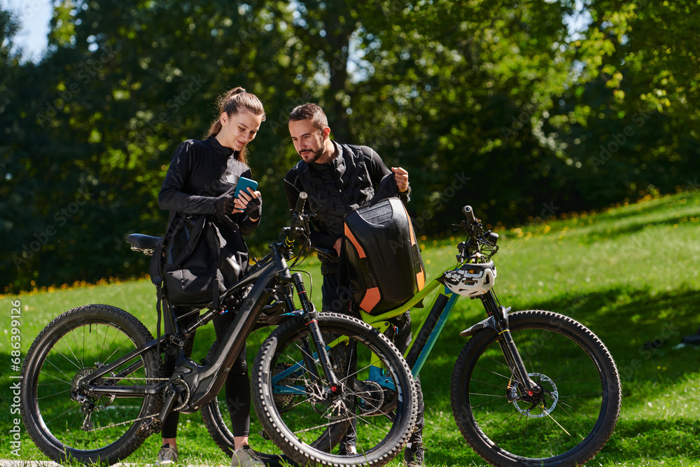A sweet couple, equipped with bicycles and engrossed in coordinating their journey, checks their GPS mobile and watches while planning scenic routes in the park, seamlessly blending technology and