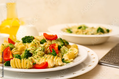 Plates of tasty pasta with broccoli and tomatoes on white background