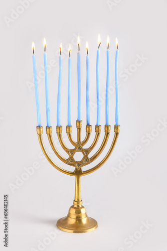 Menorah with burning candles for Hanukkah celebration on grey background