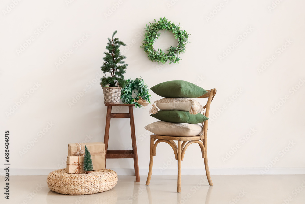 Cozy home interior with decorative pillows on chair, mini Christmas tree and mistletoe wreath