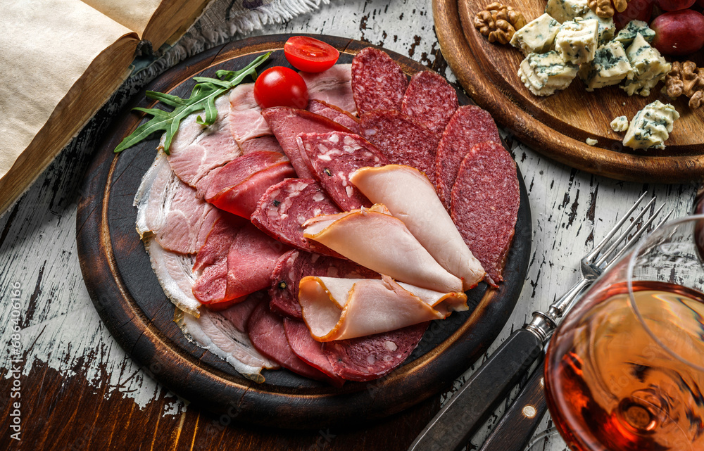 Antipasto cold meat platter with sausage, ham, salami,  parma, prosciutto, bacon decorated with cheese, vegetables on rustic wooden background with a glass of wine. Meat snacks, set of wine, top view