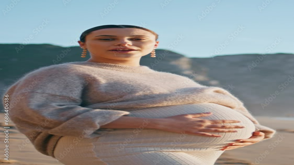 Pregnant girl posing seashore with smile vertically. Expectant mother on beach