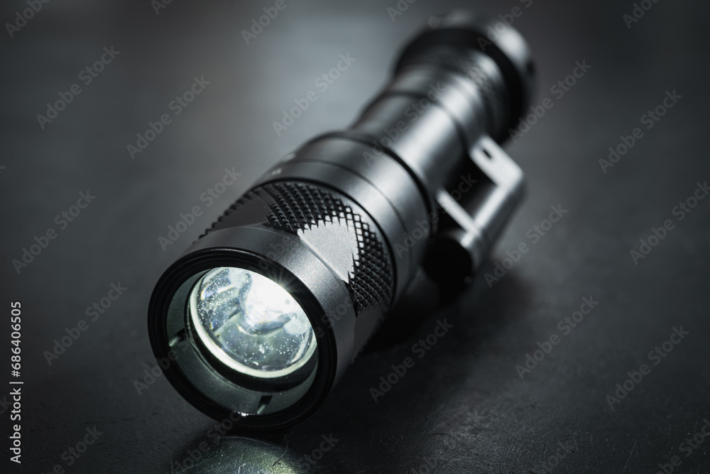 Turned on tactical flashlight, close-up photo. Turned on tactical flashlight, close-up photo.