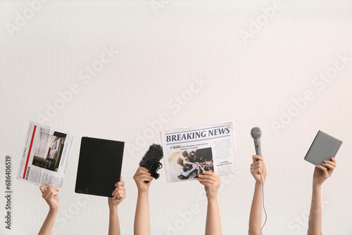 Female hands with newspapers, microphones and notebooks on light background photo