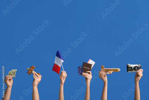 Female hands with photo camera, wooden planes, money and flag of France on blue background