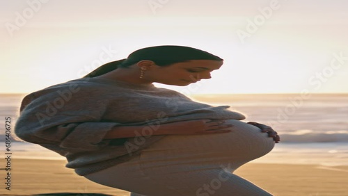 Expectant mother posing sunset beach caressing belly vertical. Pregnant woman photo