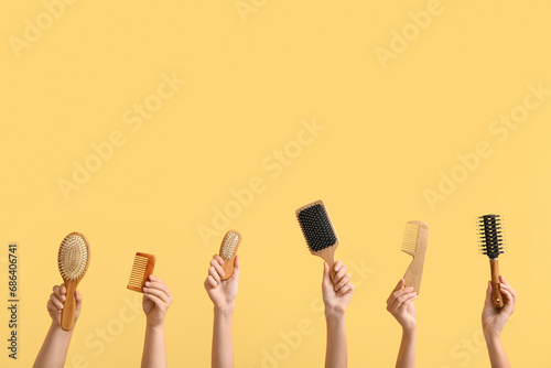 Female hands with different hair brushes and combs on color background photo