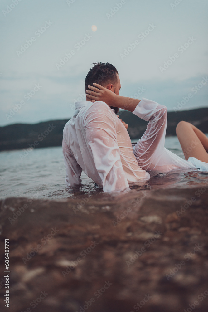 A romantic young couple sharing a passionate kiss amidst the serene beauty of the ocean at sunset. A romantic young couple sharing a passionate kiss amidst the serene beauty of the ocean at sunset.
