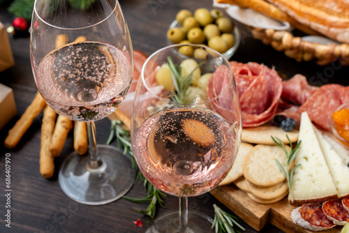 festive aperitif or party two glasses of champagne, Prosecco or rosé wine with cold meat appetizers cheeses and olives photo