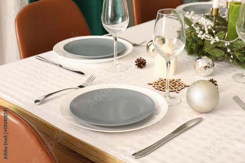 Festive table setting with clean plates  wine glasses and Christmas decorations  closeup