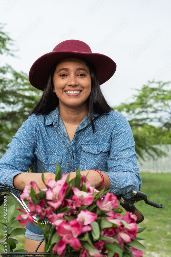 Portrait of a Latin woman seated on her bicycle with flowers
