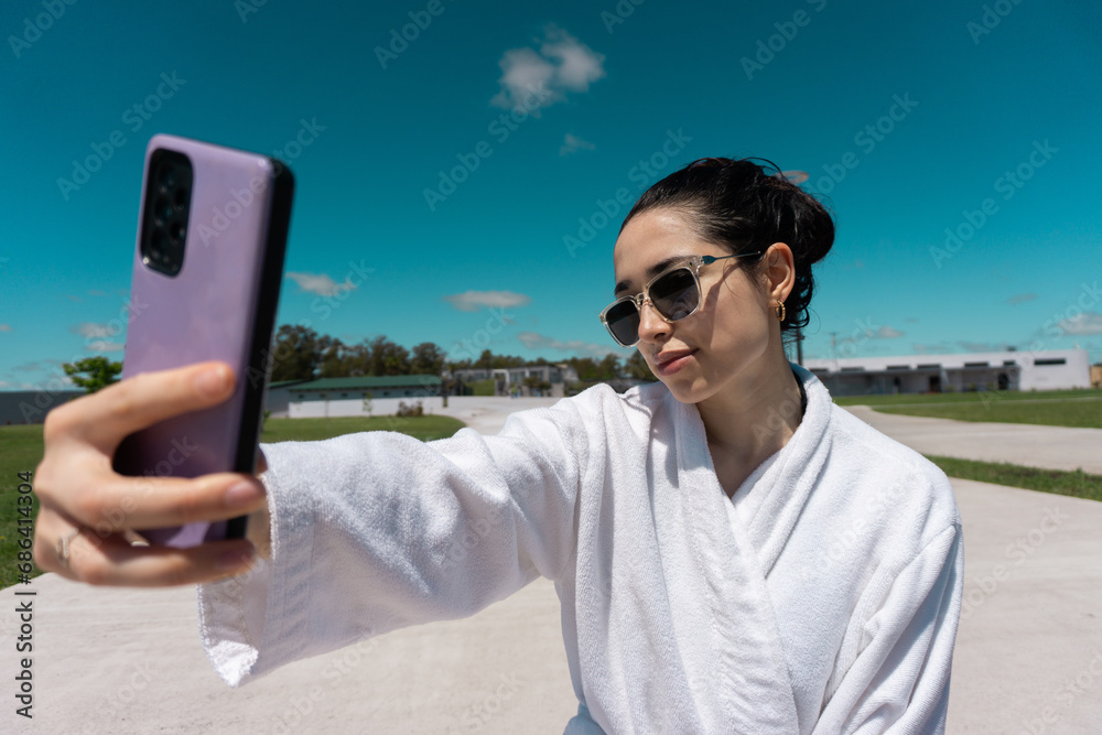 beautiful woman taking a photo near a pool in a bathrobe