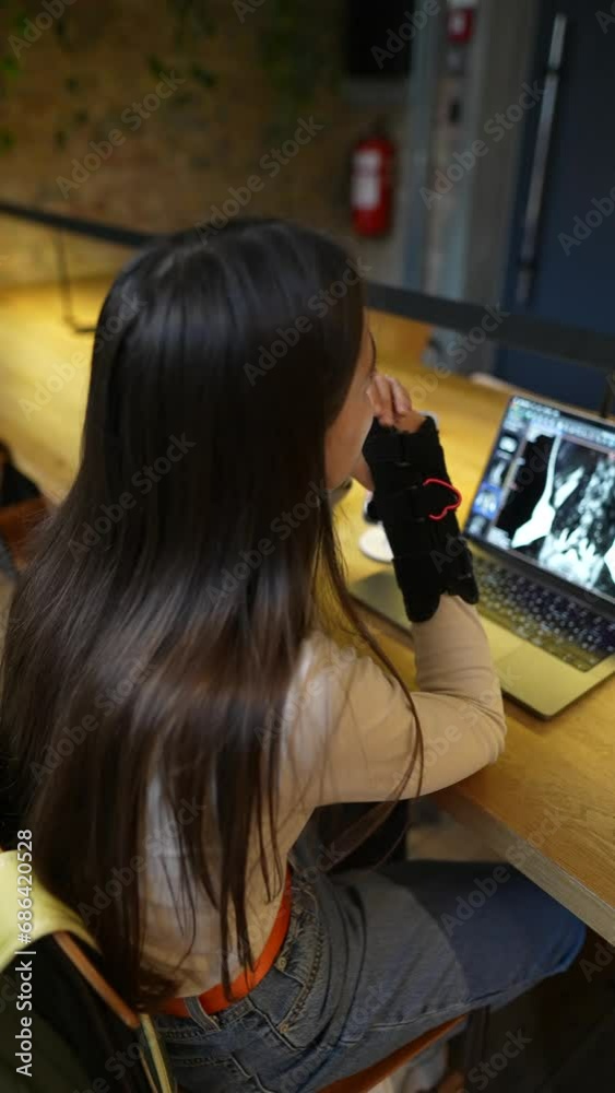 In a cafe, a young and lovely student sits with a laptop, talking with someone. In a cafe, a young and lovely student sits with a laptop, talking with someone.