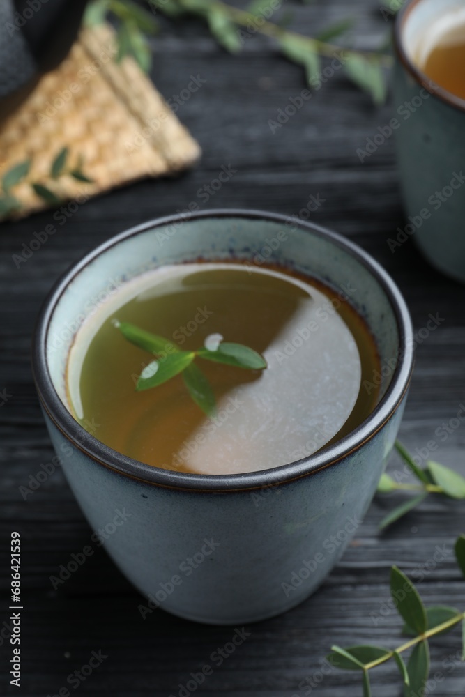 Cup of aromatic eucalyptus tea on black wooden table, closeup Cup of aromatic eucalyptus tea on black wooden table, closeup