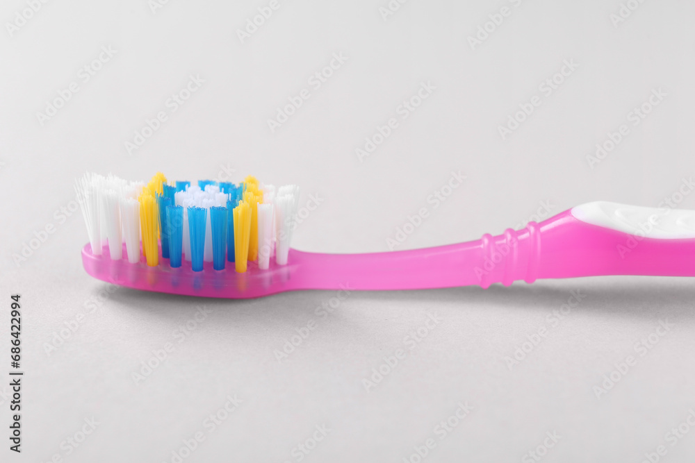 One plastic toothbrush on light background, closeup One plastic toothbrush on light background, closeup