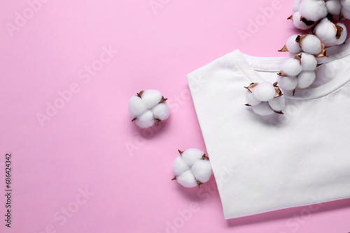 Cotton branch with fluffy flowers and white t-shirt on pink background, flat lay. Space for text © New Africa