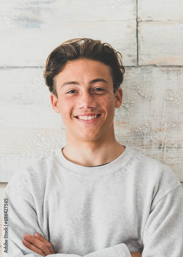 one teenager at home smiling happy at the camera - simple photo of handsome young man looking with wooden wall at the background