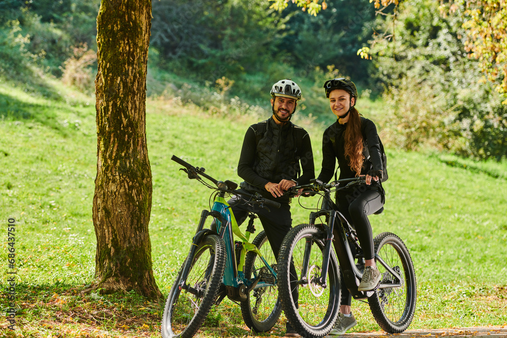 Obraz premium A blissful couple, adorned in professional cycling gear, enjoys a romantic bicycle ride through a park, surrounded by modern natural attractions, radiating love and happiness