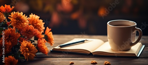 Macro picture of a pen with an orange flower blurred coffee cup and books in the foreground