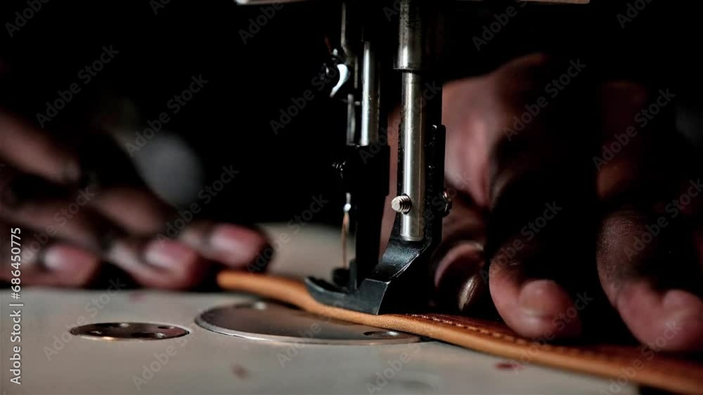 Black man using a sewing machine to sew leather straps