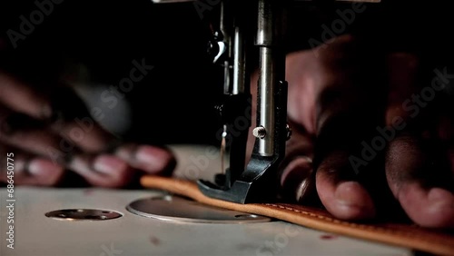 Black man using a sewing machine to sew leather straps photo
