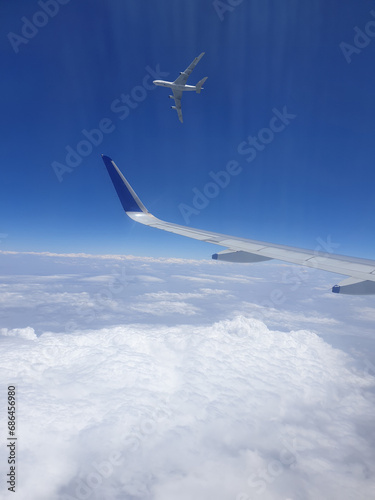 An view of an aircraft flying past another aircraft, viewed from an aircraft window.