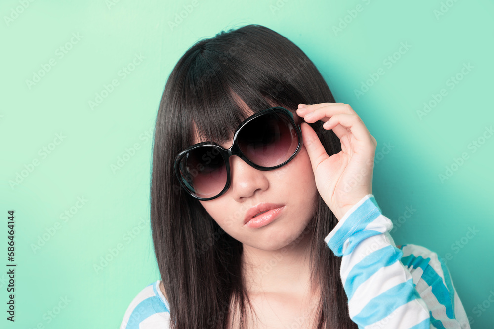 Cool Asian woman leaning against a wall with sunglasses. Cool Asian woman leaning against a wall with sunglasses.