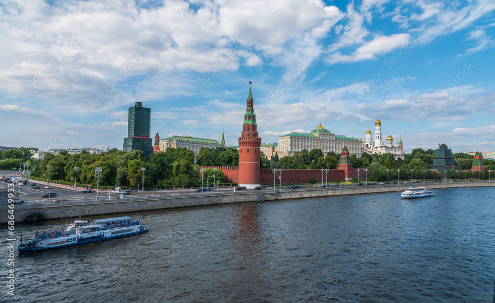 View of Kremlin with Vodovzvodnaya tower, Grand Kremlin Palace from repaired Bolshoy Kamenny Bridge in Moscow city on sunny summer day. Cruise ship sails on the Moscow river